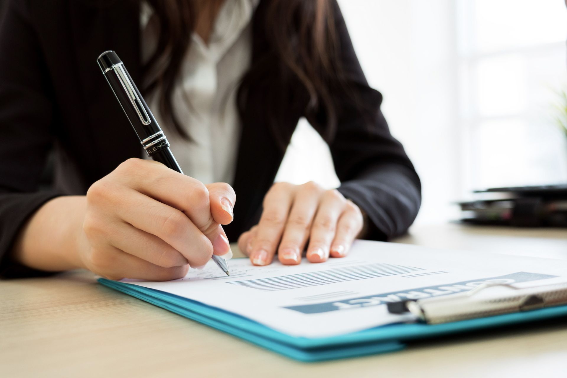 A woman is writing on a clipboard with a pen.