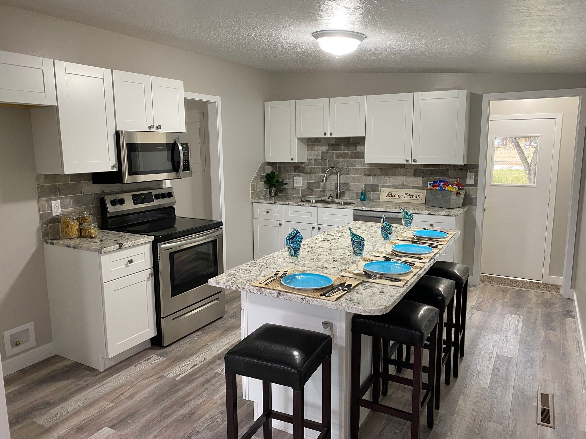 A kitchen with a large island in the middle and stools.