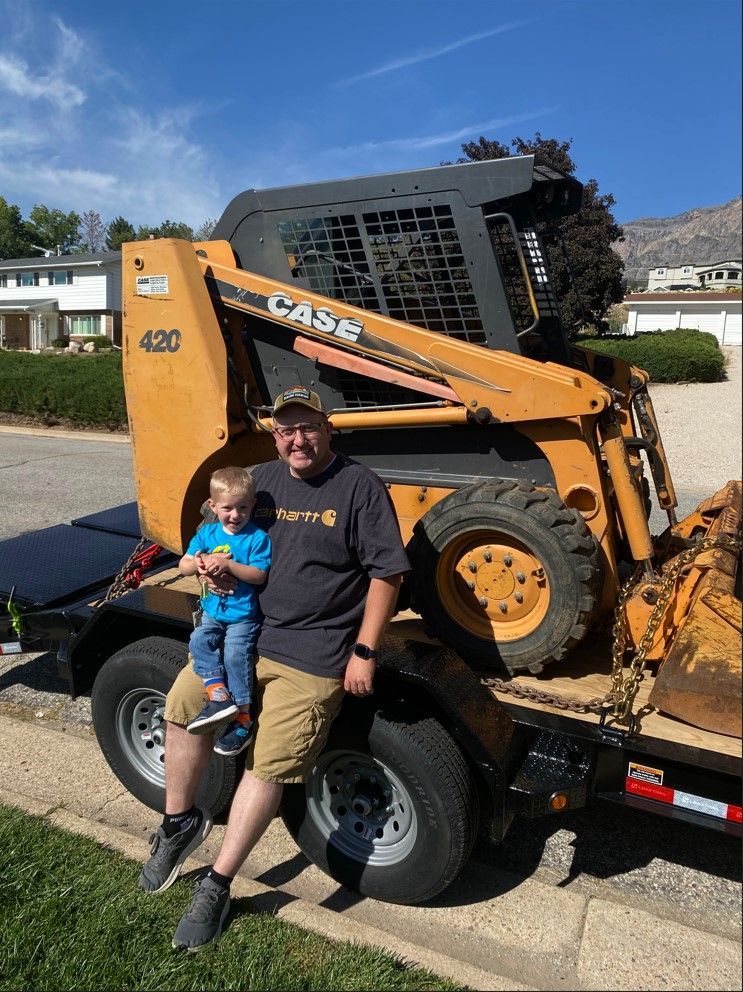 A man is holding a child in front of a case tractor.