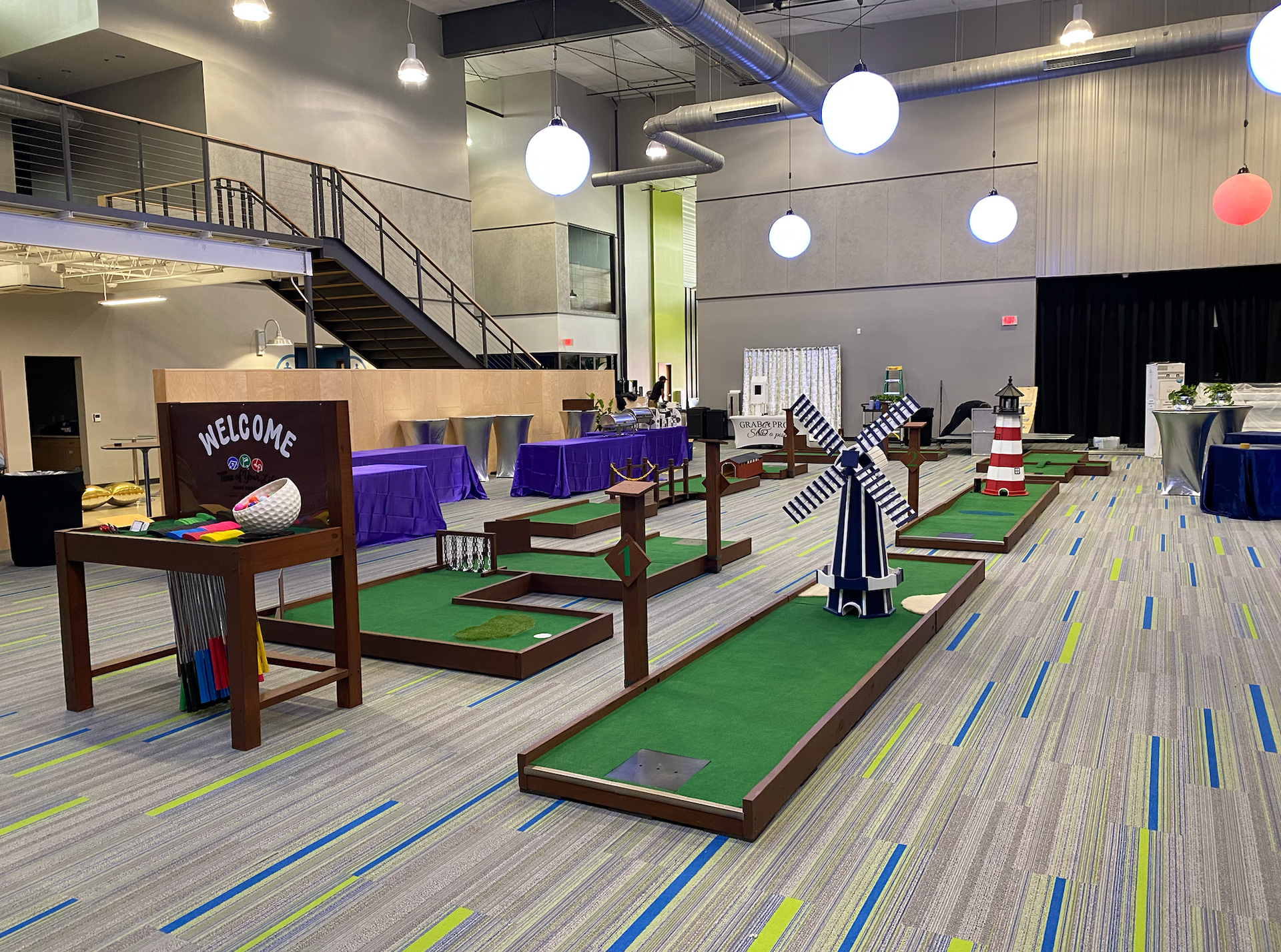 A large room filled with mini golf courses and tables.