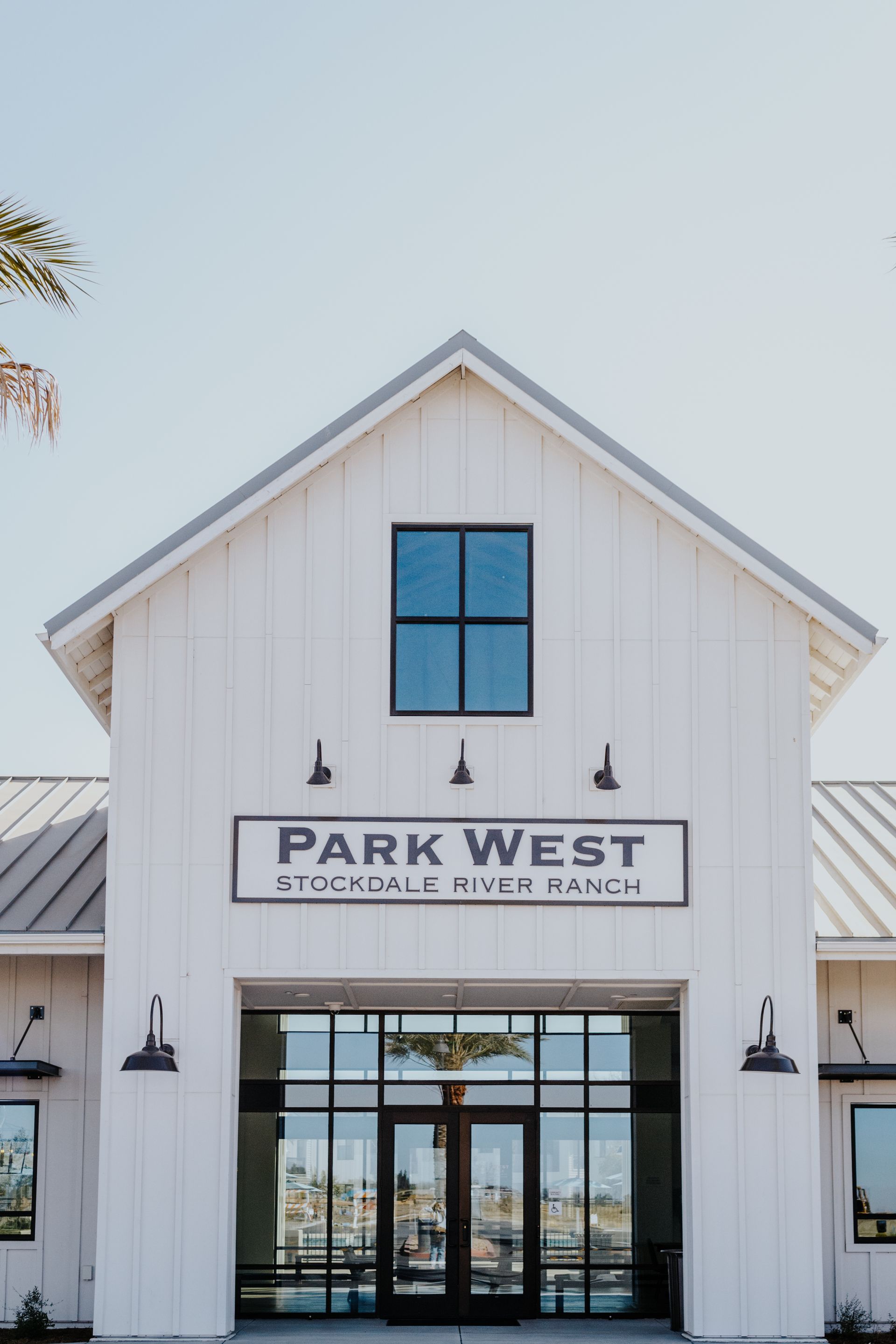 The front of a white building with a roof and a sign that says park west.