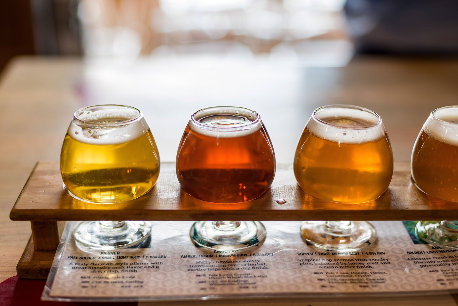 Four glasses of beer are sitting on a wooden tray.