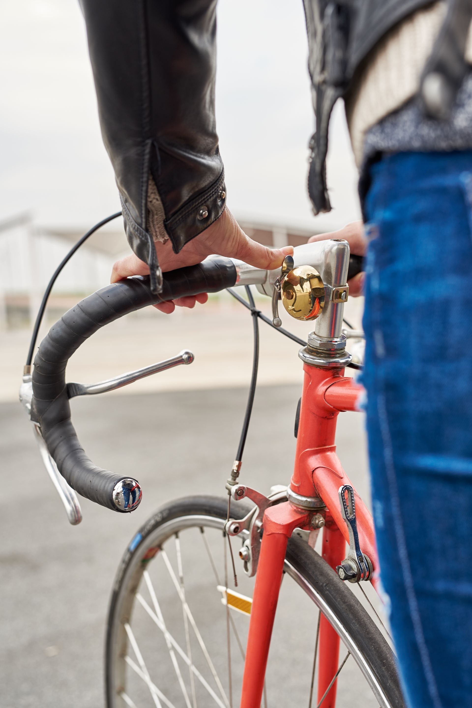 A person is holding the handlebars of a red bicycle.