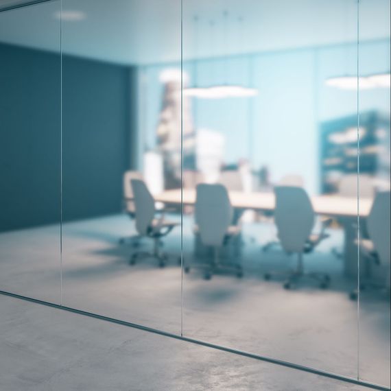 A blurry view through a glass partition into a modern, minimalist conference room with white chairs and a long table.