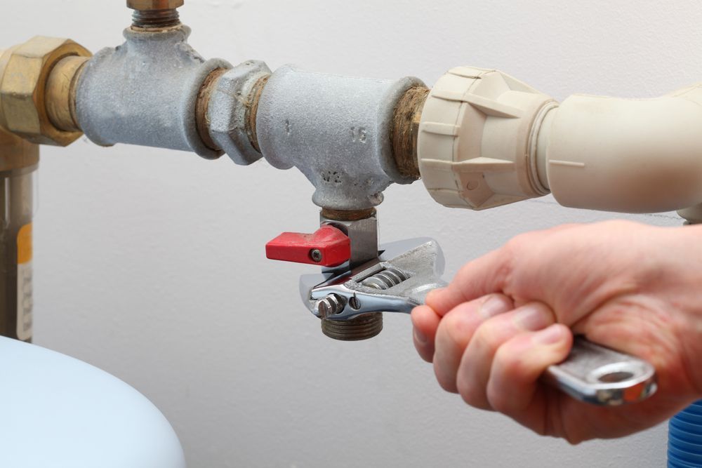A Person is Fixing a Pipe With a Wrench — Chad Warrington Plumbing In New Lambton, NSW