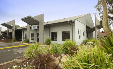 A large white building with a lot of windows is surrounded by tall grass.