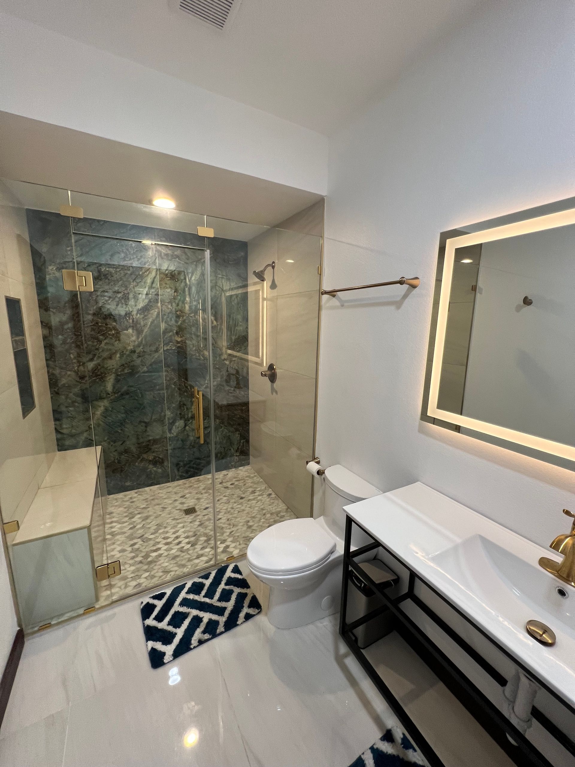 A bathroom with a toilet , sink , shower and mirror.