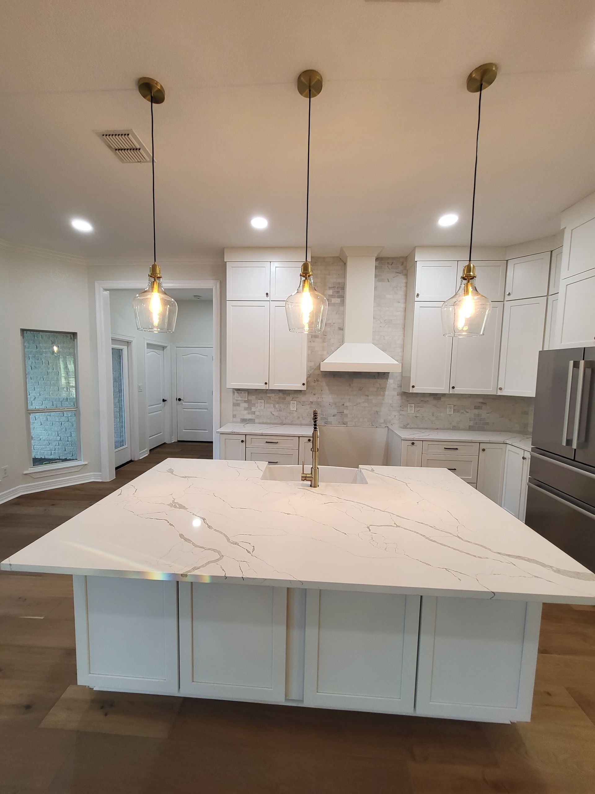 Bright white modern kitchen with large island, pendant lights, and white cabinetry