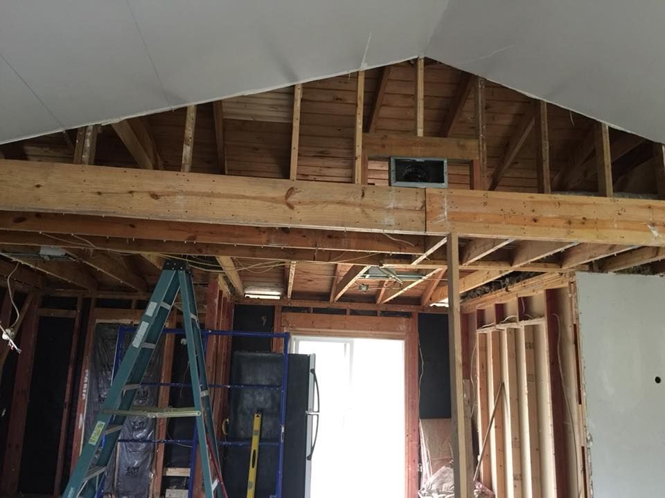 Partially demolished room with exposed wooden framing, insulation, and a bright doorway during renovation