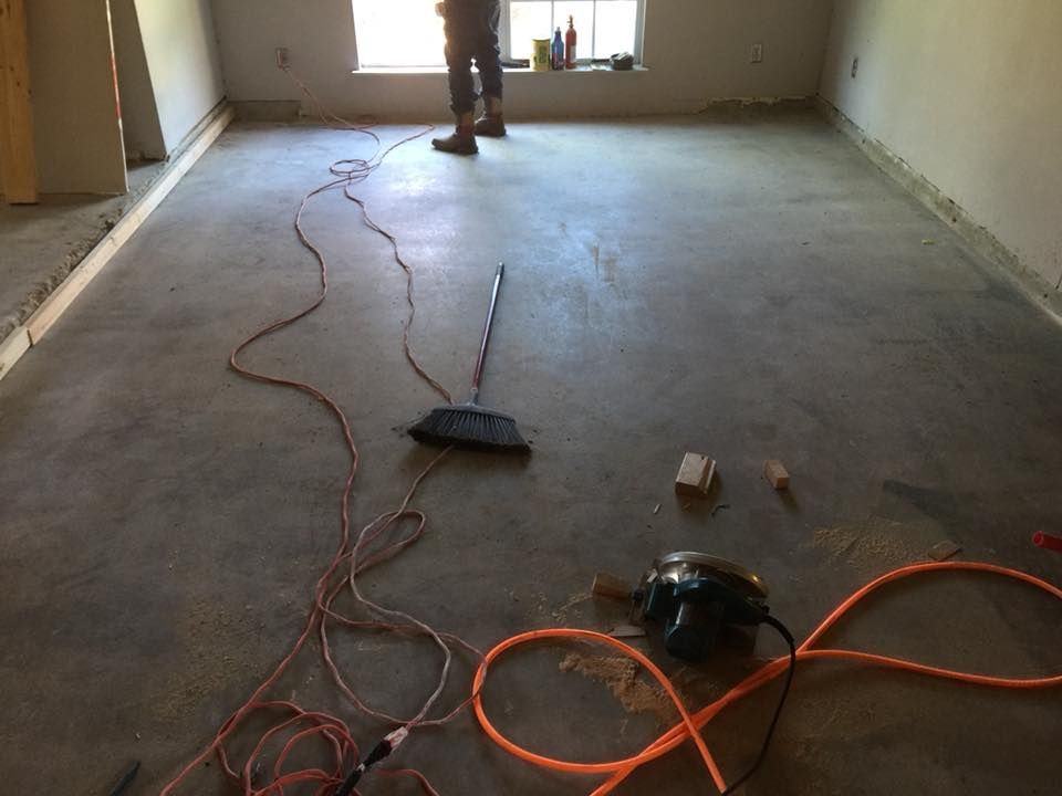 Bare room with unfinished concrete floor, power cords, and tools during renovation