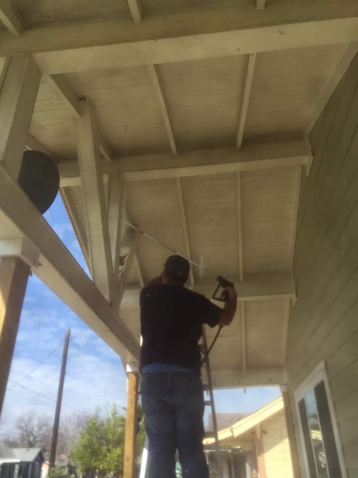 Person working overhead on a porch ceiling with a tool, viewed from below.