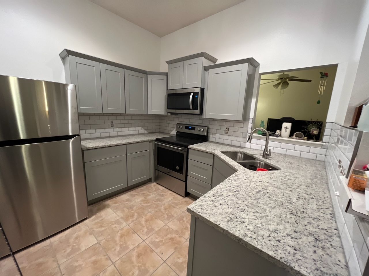Modern kitchen with stainless steel appliances, gray cabinets, and granite countertops