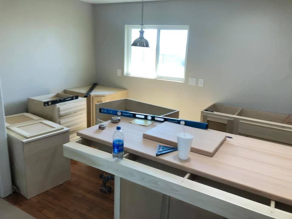 Unfinished room with workbench, tools, and window; blue bottle and cup on a table.