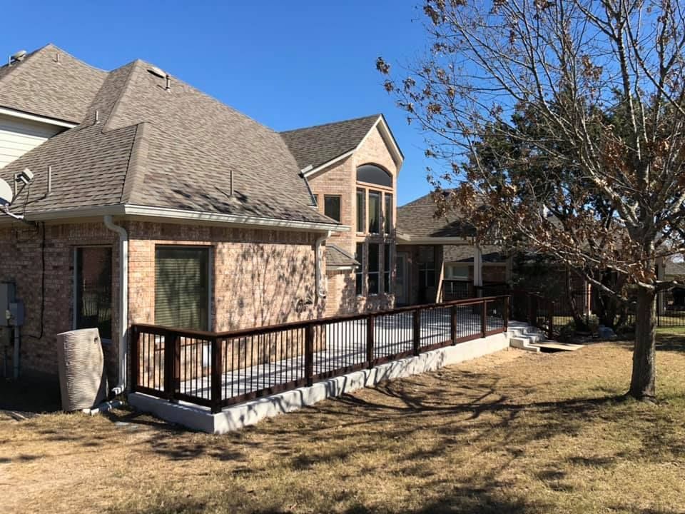 Suburban house with a large wooden ramp leading to a back deck and yard under a clear blue sky