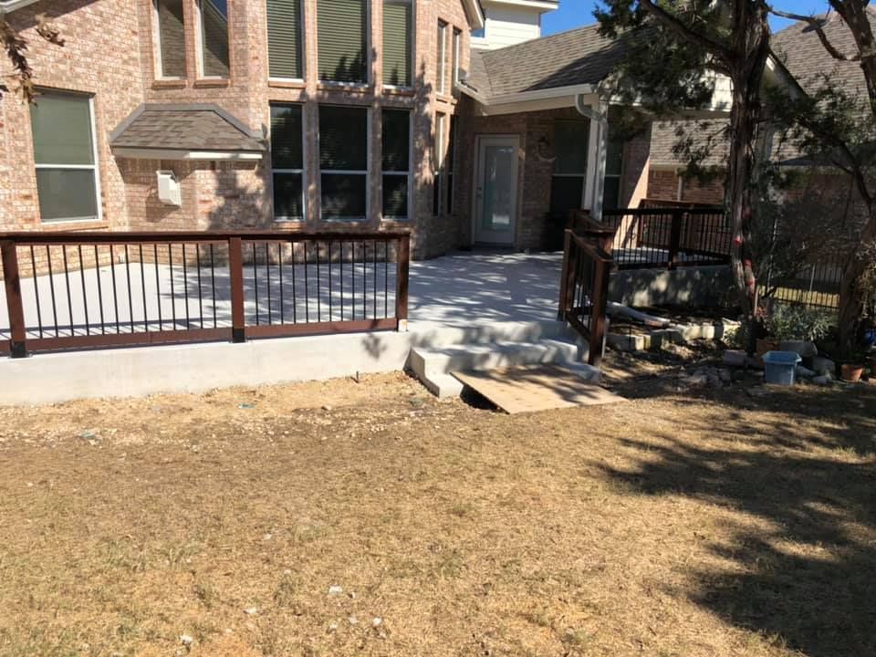 Front yard patio with stone house, black railing, and a small bench in winter sunlight