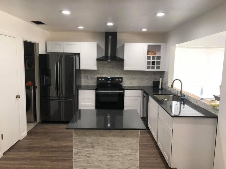 Modern kitchen with white cabinets, black appliances, and a gray island countertop