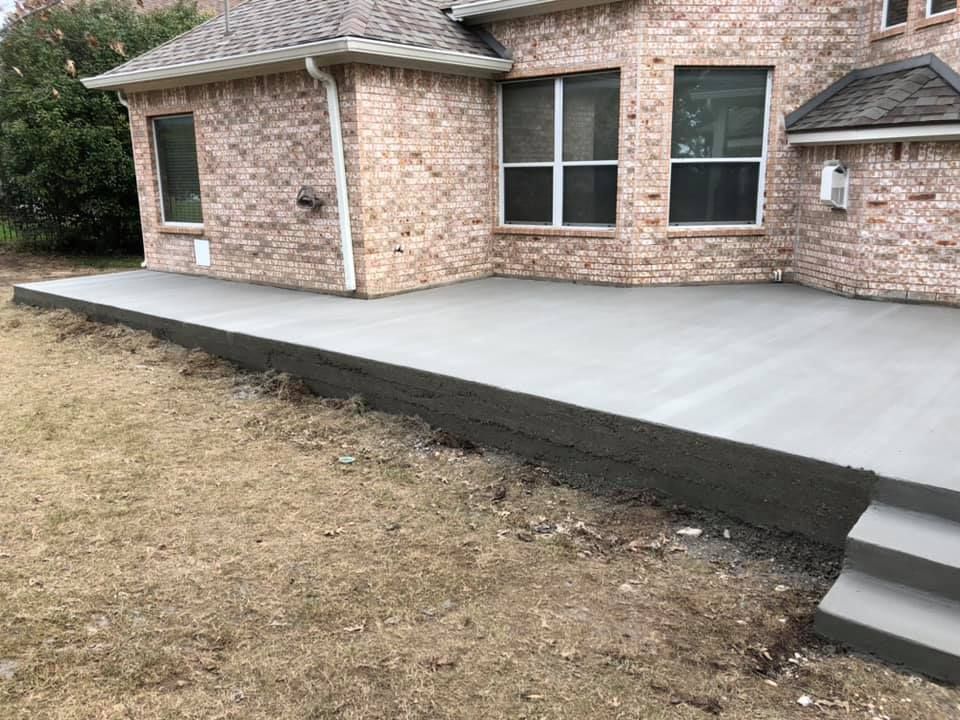 A brick house with a concrete patio in front of it.