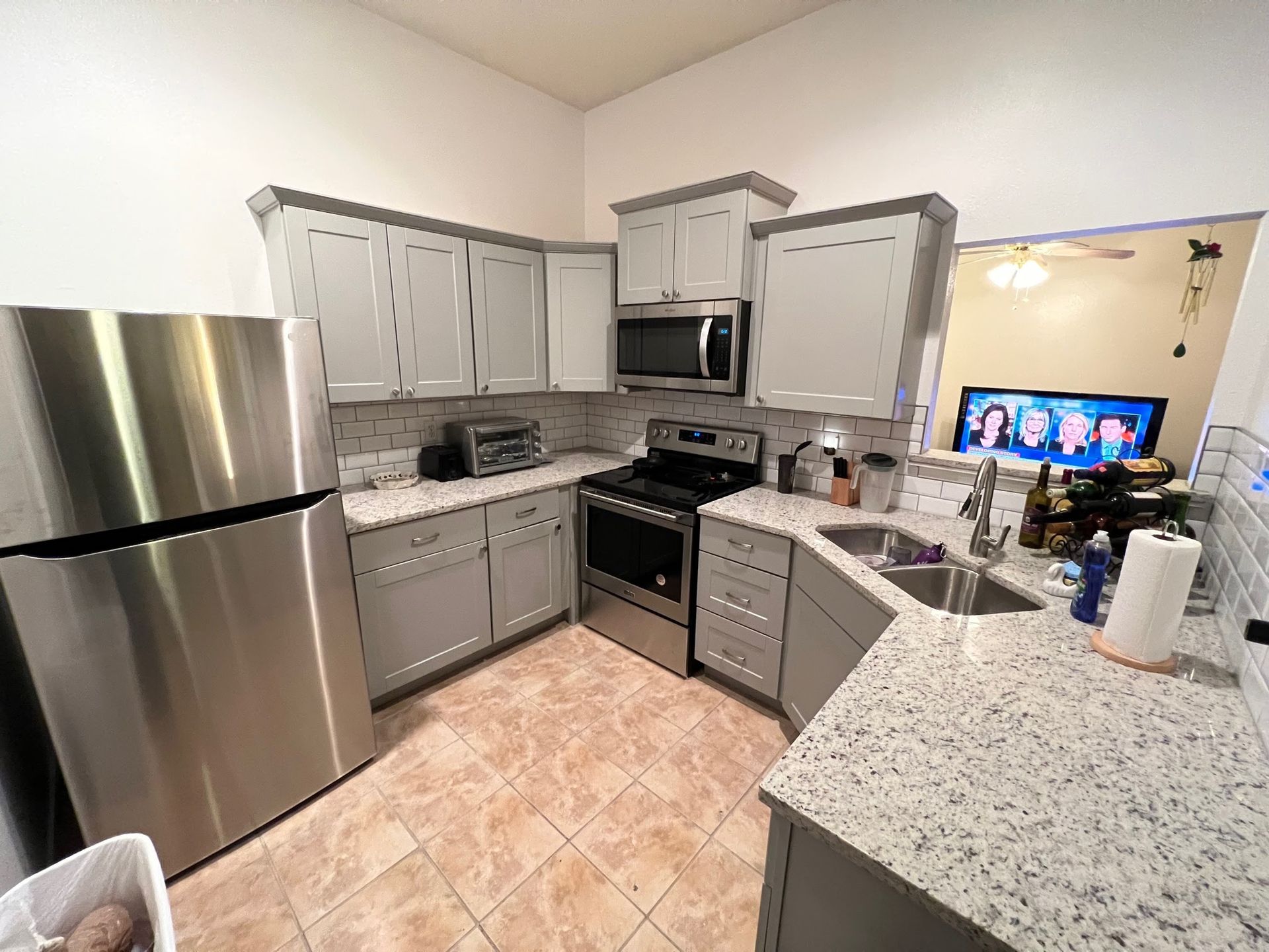 Modern kitchen with stainless steel appliances, gray cabinets, and speckled countertops.
