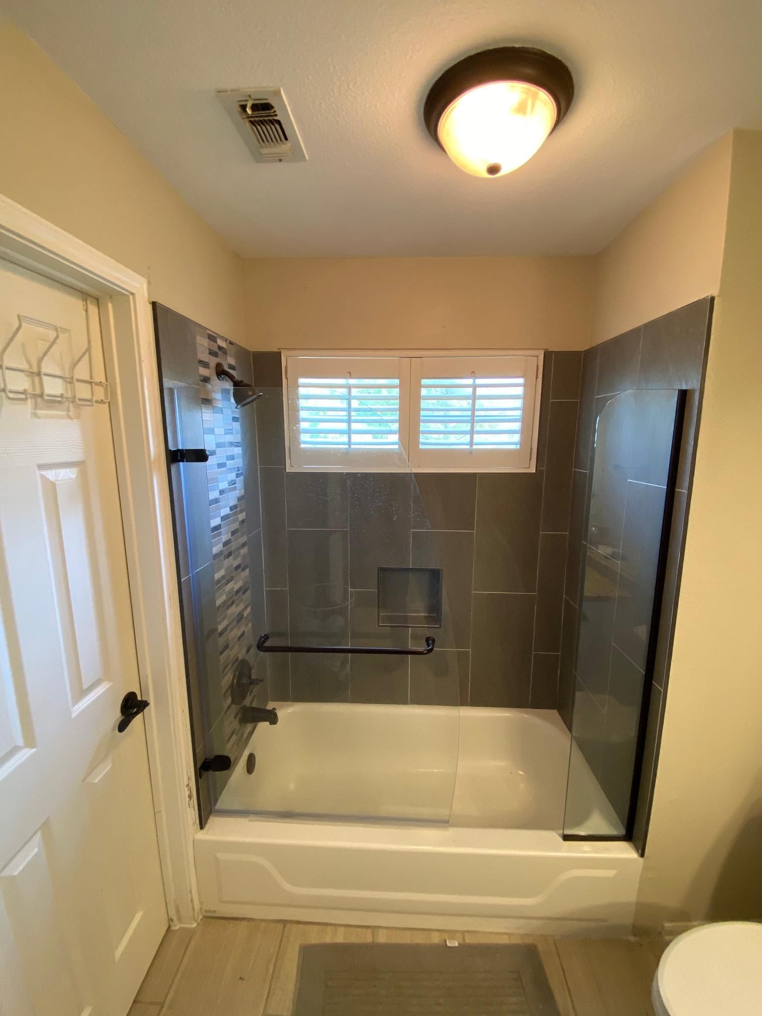 A bathroom with a tub and a shower with a glass door.
