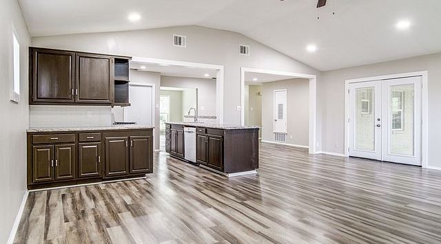 Spacious open-plan kitchen and living area with dark wood cabinets and light wood floors