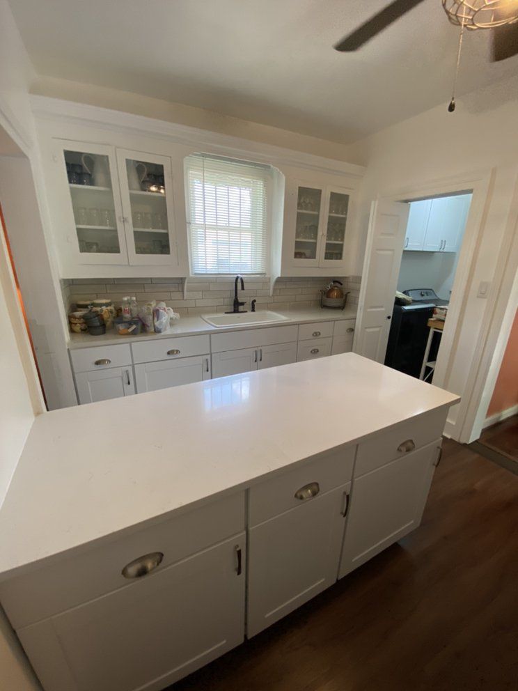 A kitchen with white cabinets and a large island in the middle.