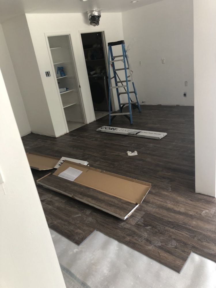 Unfinished room with wood flooring, ladder, open closet, and construction materials on the floor.