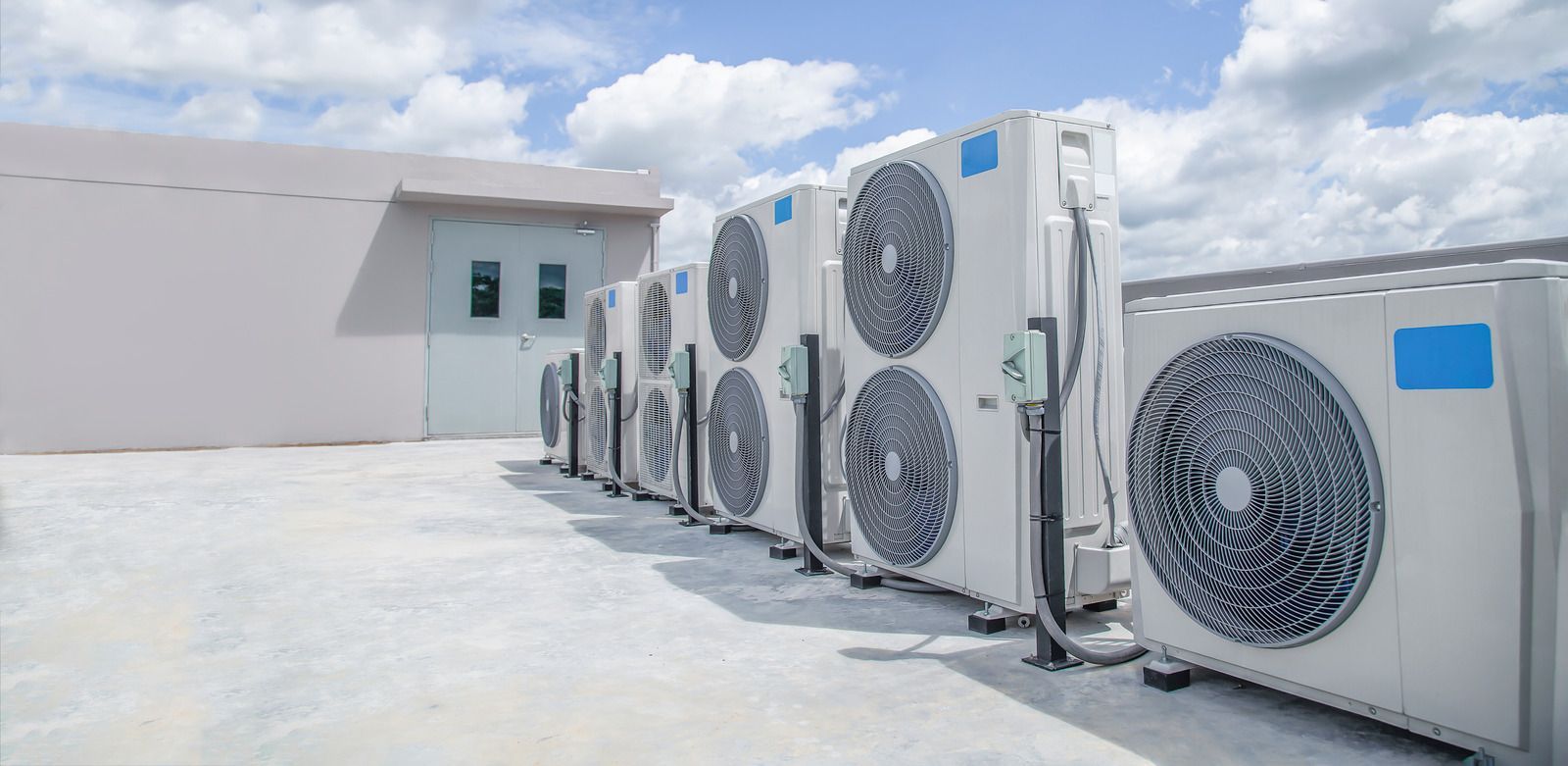 A row of air conditioners are lined up on the roof of a building.