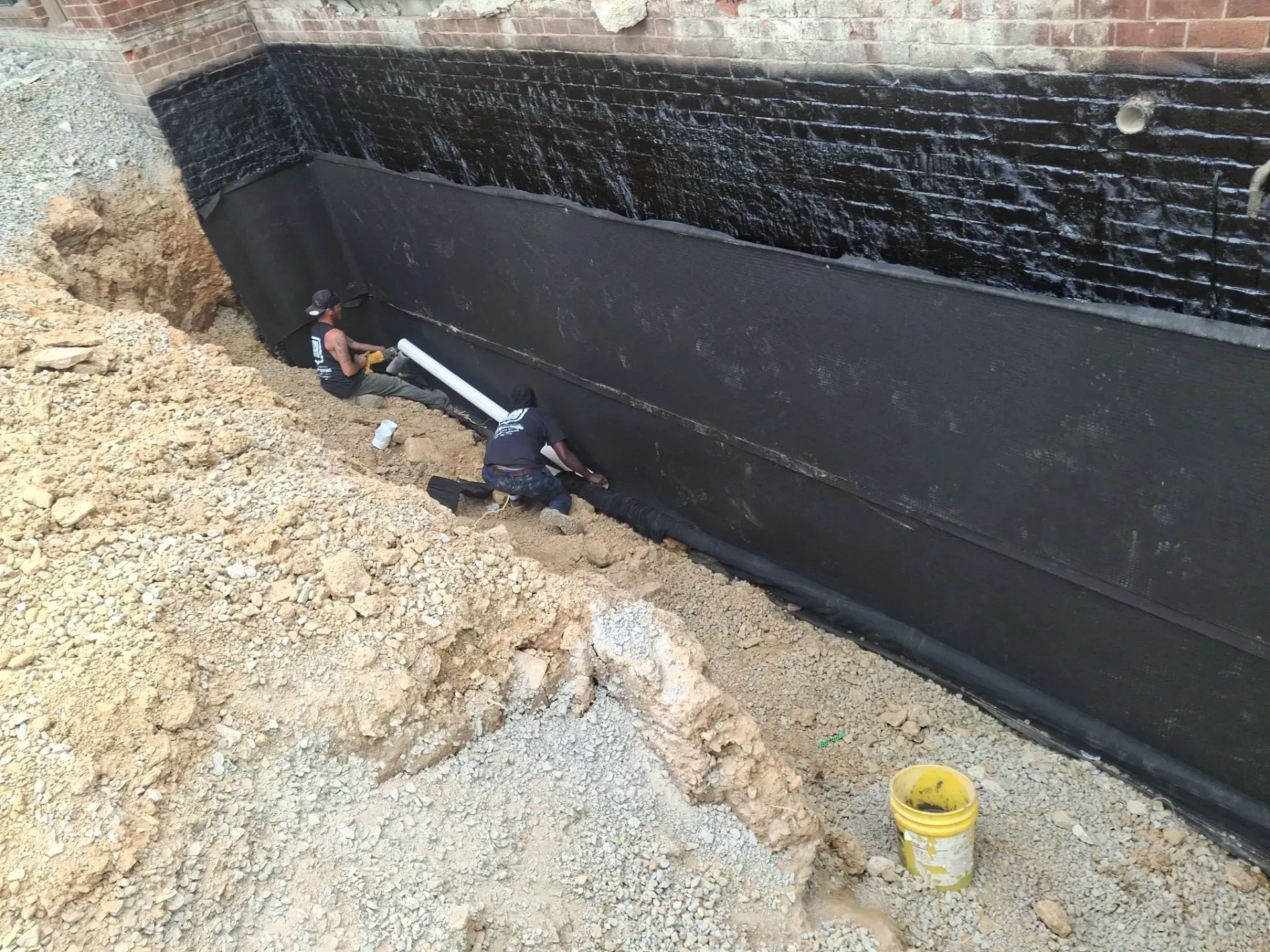 Drainage board installation over exterior waterproofing membrane on Alabama foundation