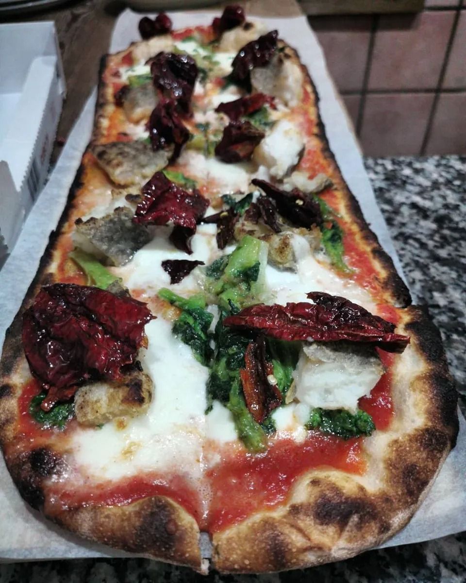 Pizza rettangolare con formaggio fuso, salsa di pomodoro e basilico su carta da forno su un tavolo