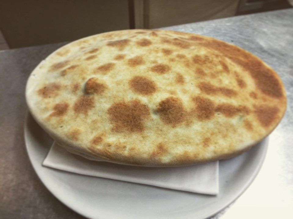 Round flatbread on a plate, golden-brown with toasted spots