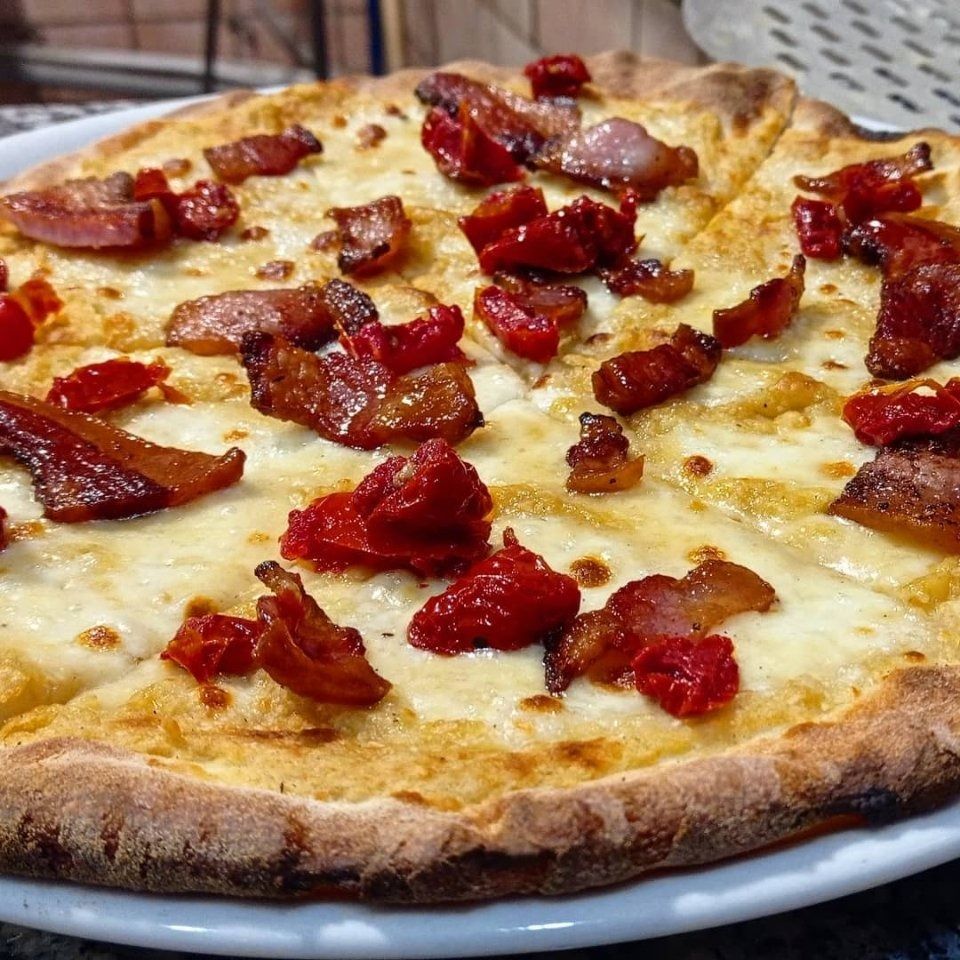Pizza al formaggio con peperoni rossi su un piatto bianco