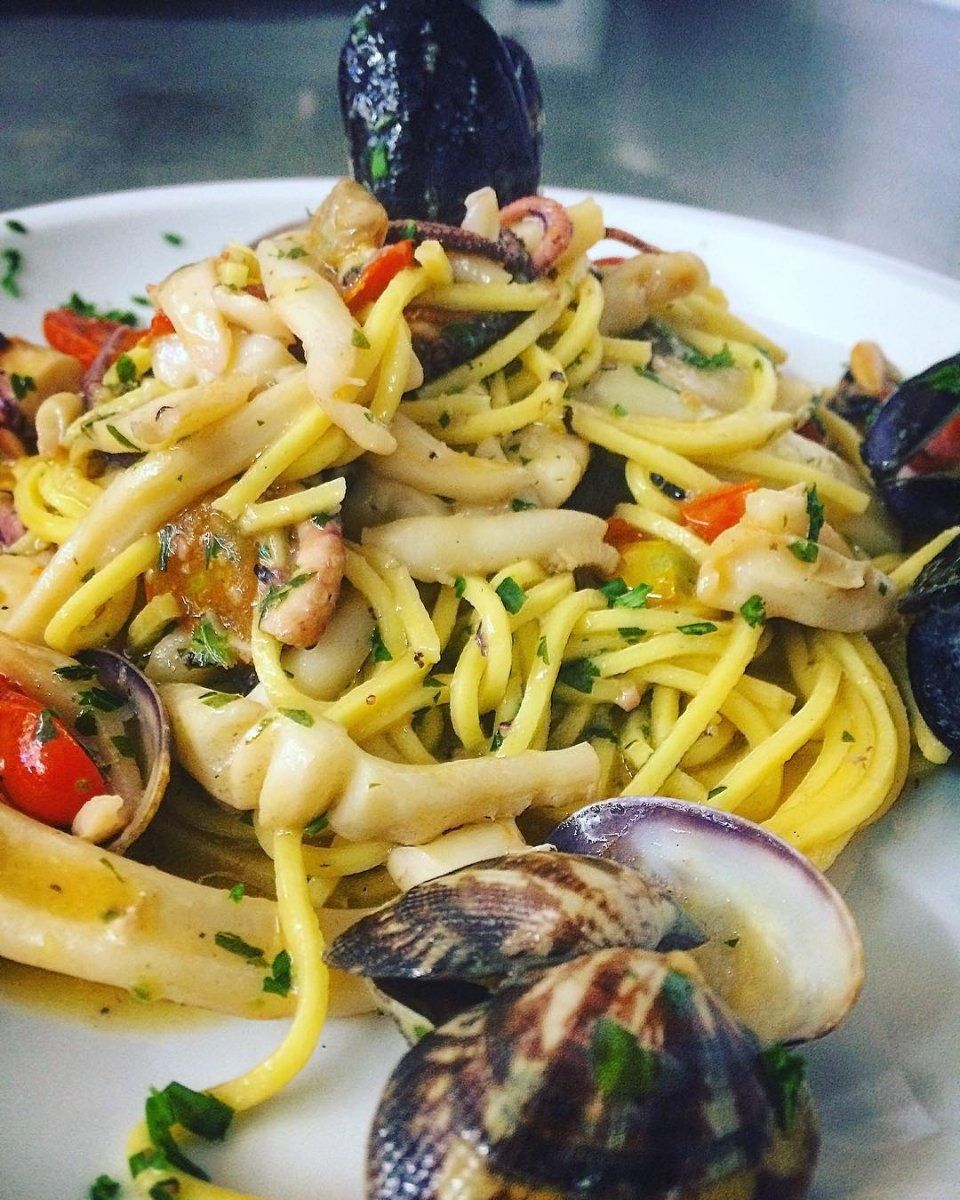 Pasta with clams, mussels, and cherry tomatoes in a white bowl