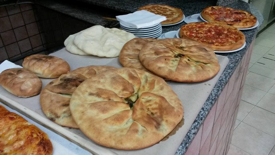 Assorted baked breads and pizzas displayed on a bakery counter