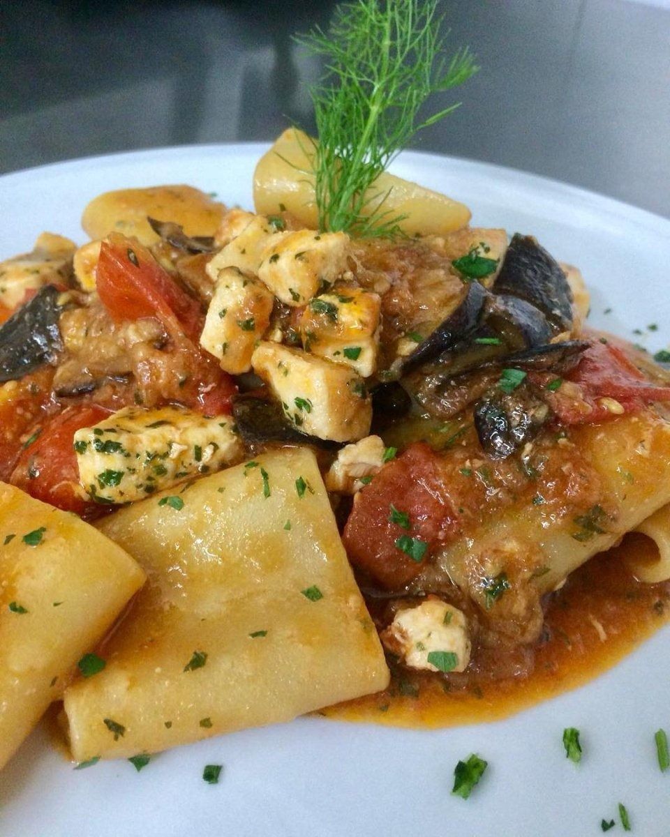 Pasta with tomato sauce, mushrooms, and herbs on a white plate, garnished with dill