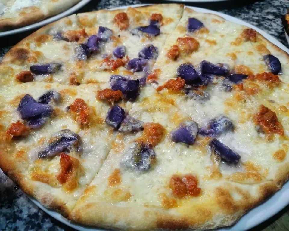 Primo piano di una pizza al formaggio con pezzi di cipolla rossa su un piatto.