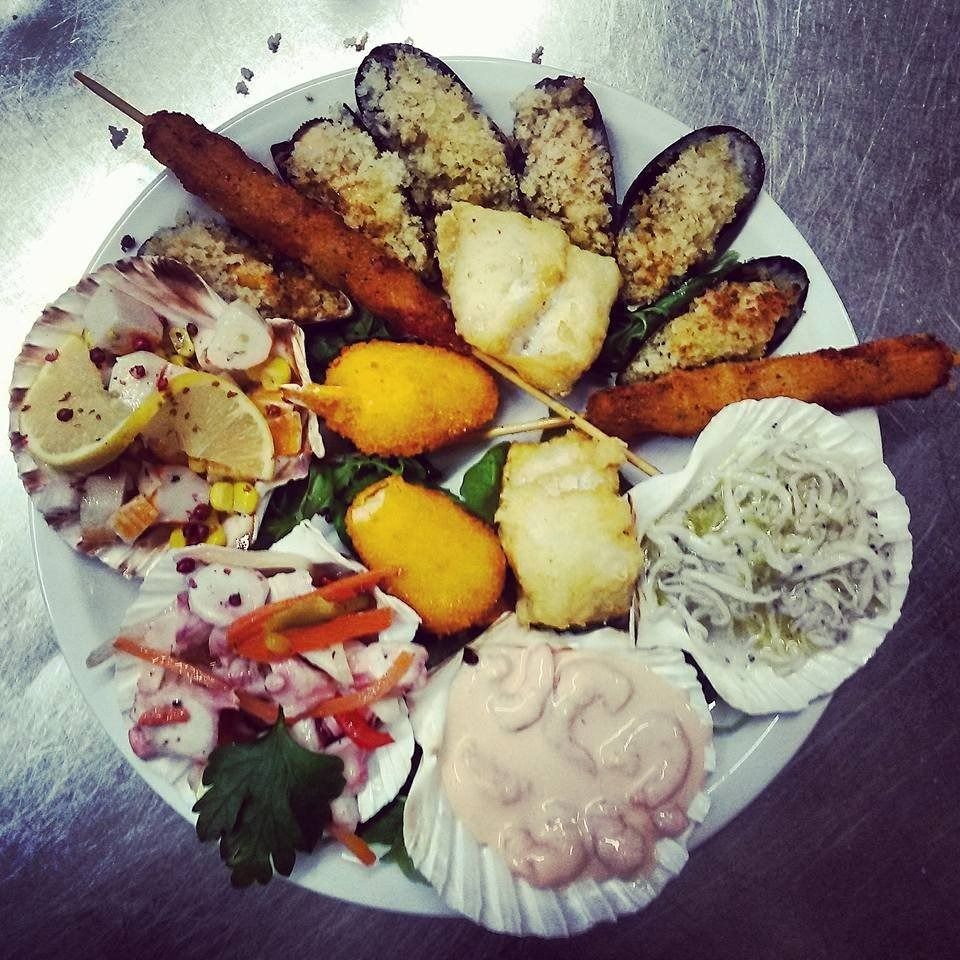 Plate of assorted appetizers and salads, including skewers, sliced rolls, and dips, arranged on a round platter