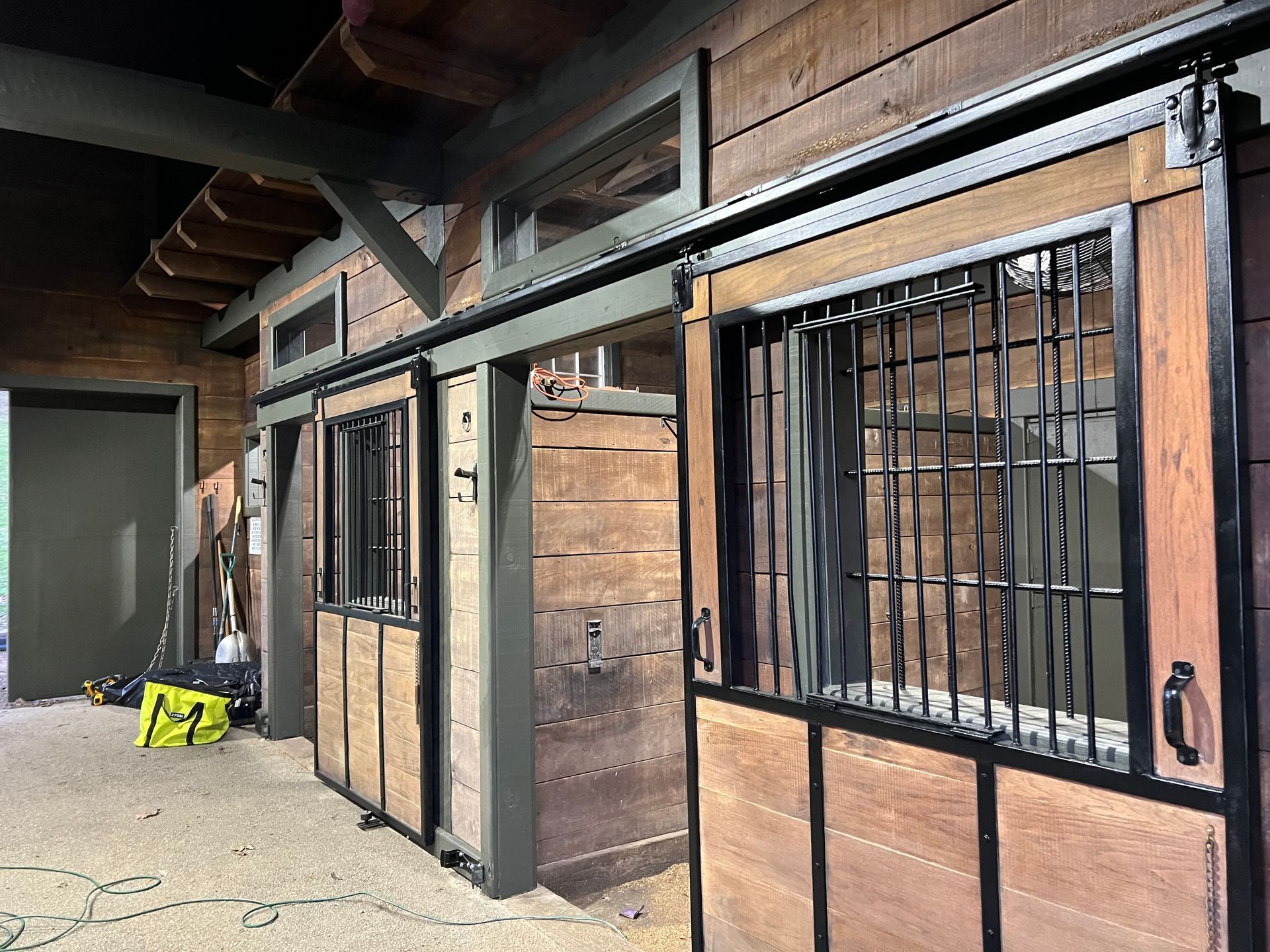 A row of wooden stables with sliding doors and windows.
