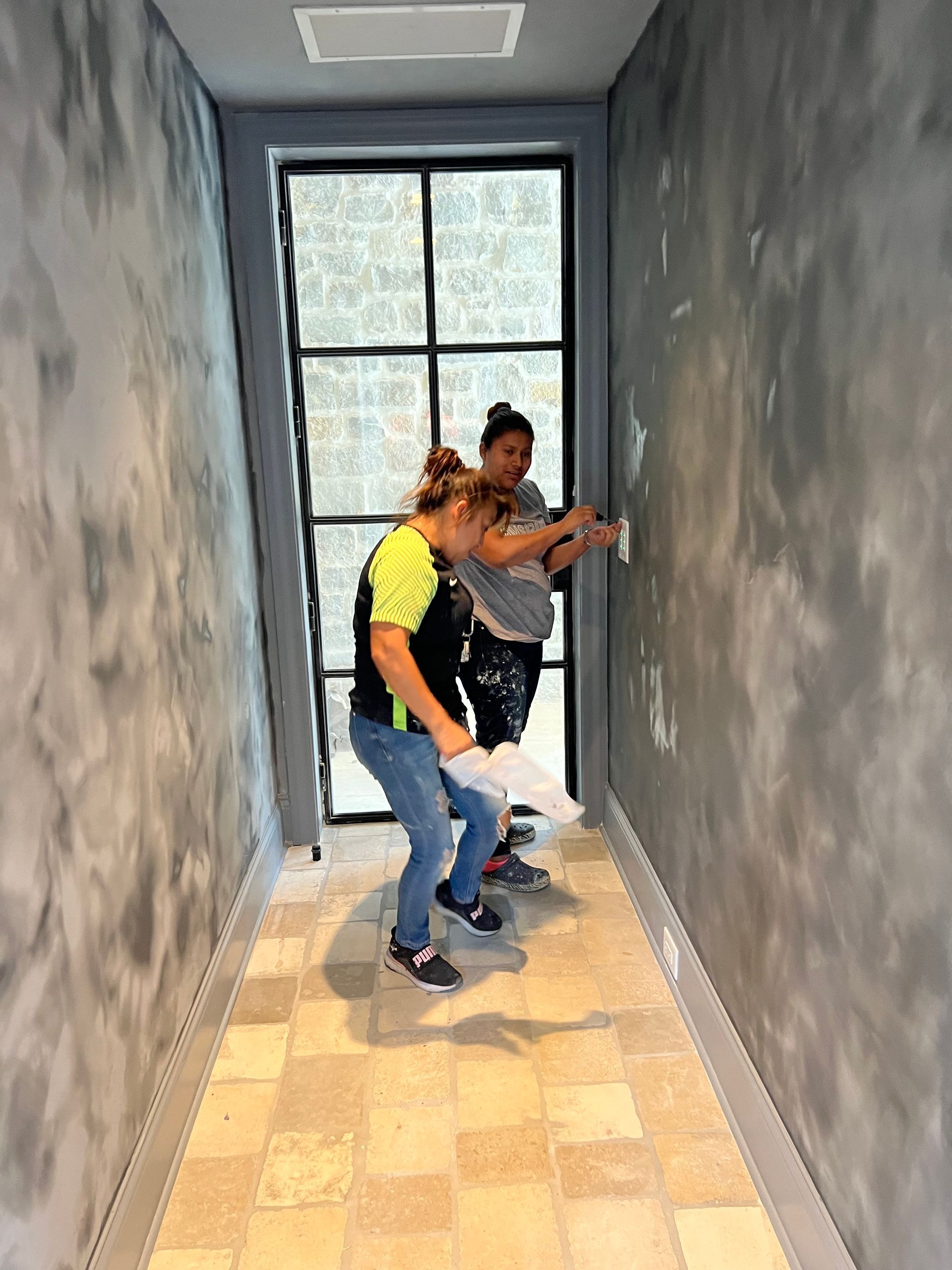 Two people are standing in a hallway looking at a wall.