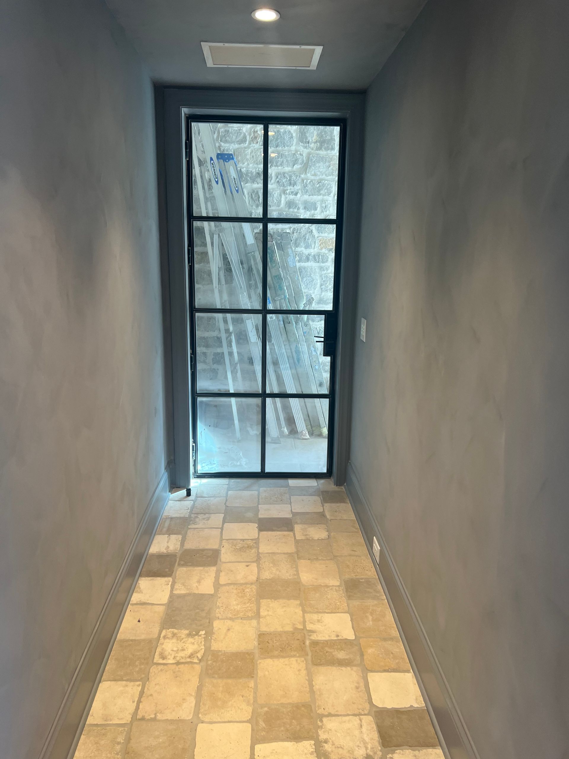 A hallway with a door and a tiled floor.