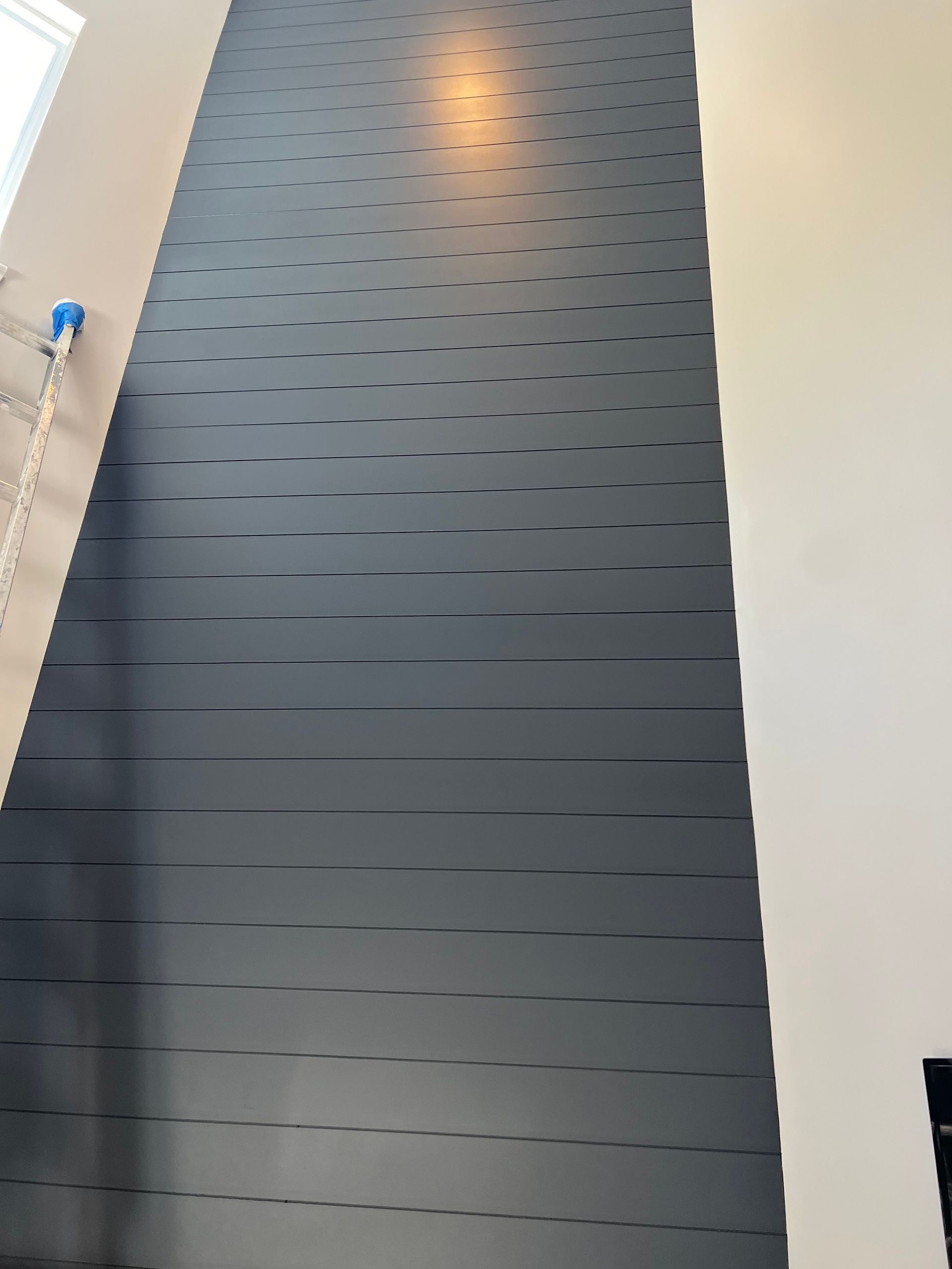 A wall with a pattern of lines on it is being painted black.