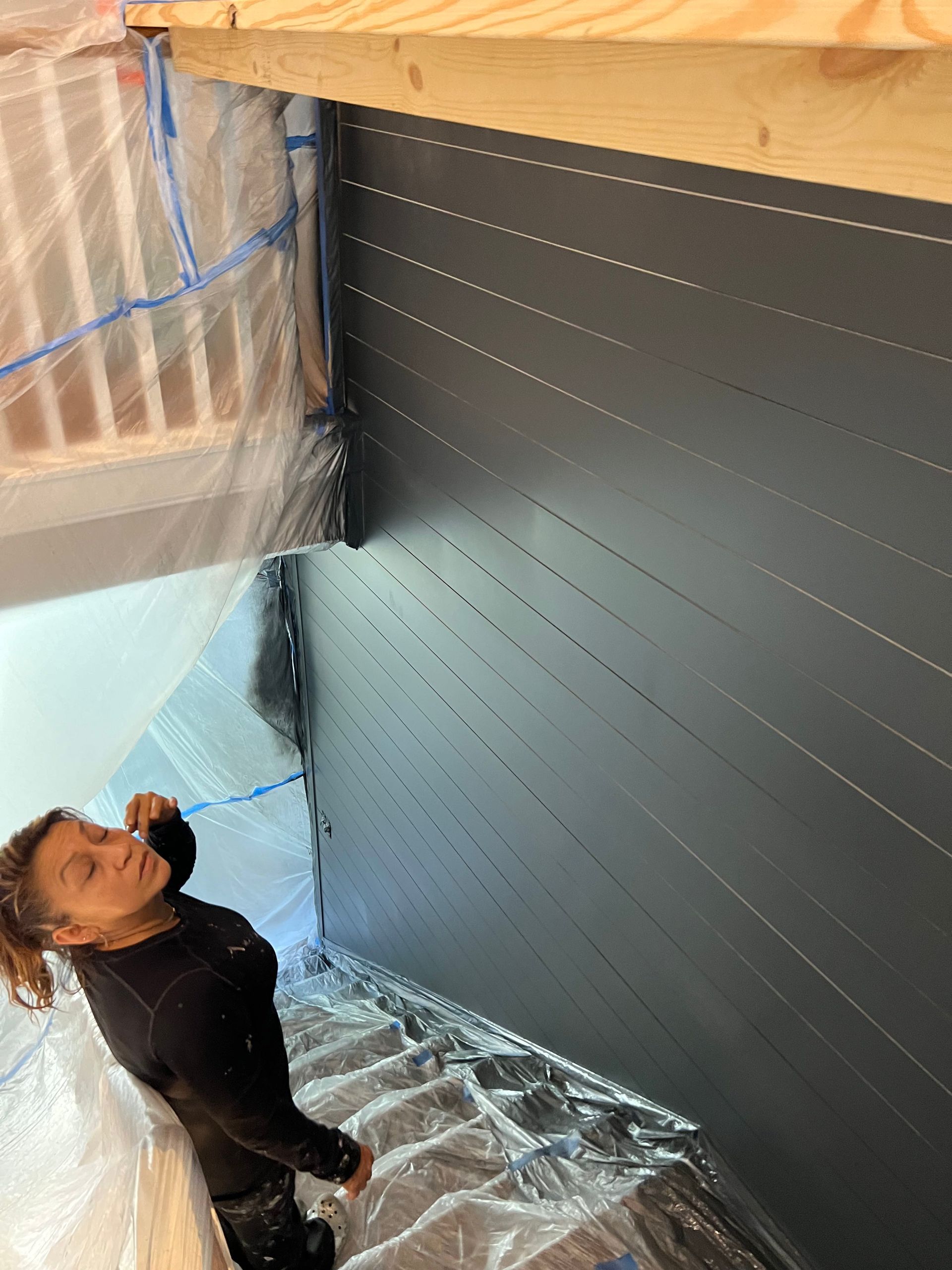 A man is standing on a set of stairs painting a wall.