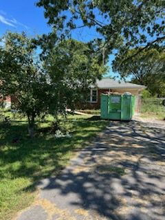 A green dumpster is parked in front of a house.