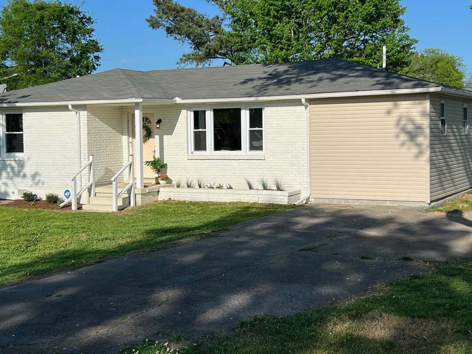 A white house with a garage and a driveway in front of it.