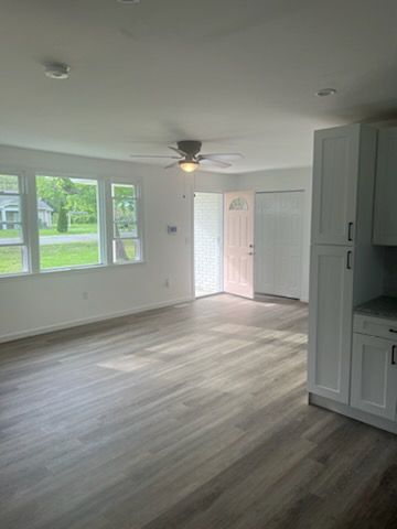 An empty living room with hardwood floors and a ceiling fan.