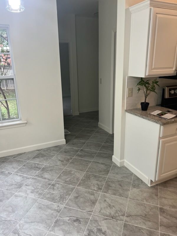 A kitchen with a gray tile floor and white cabinets.