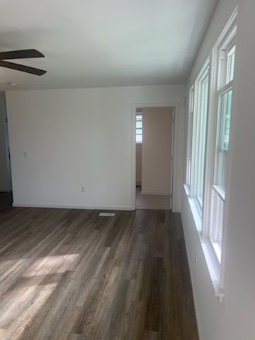 An empty living room with hardwood floors and a ceiling fan.
