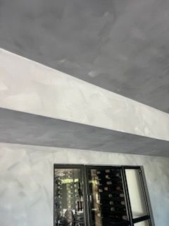 A room with a gray ceiling and a wine cellar in the background.
