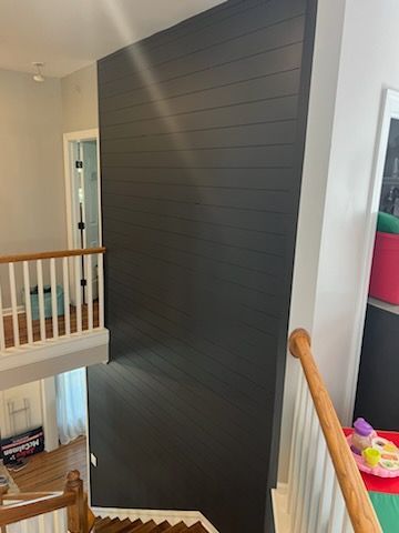 A staircase in a house with a black wall and a wooden railing.