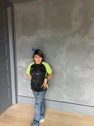 A young boy is standing in front of a gray wall in a room.