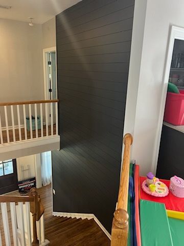 A staircase in a house with a black wall and a wooden railing.